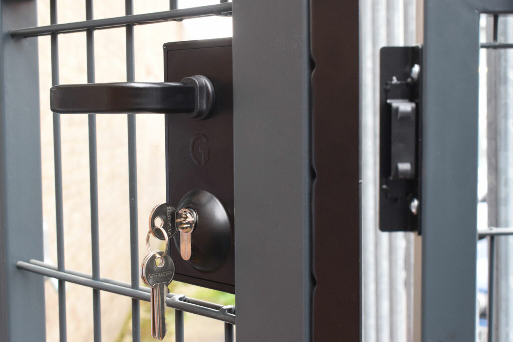 Black gate lock with keys in lock on a metal gate